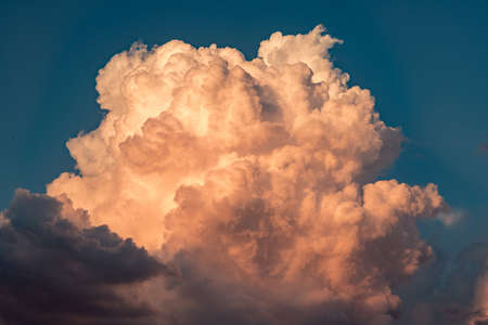 Huge cumulus cloud in the sunset orange sun raysの写真素材