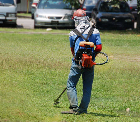a worker cutting grass with motorised cutterの写真素材
