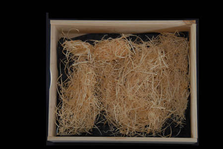 wooden box with packaging material ready to insert gift or presents in black back groundの写真素材