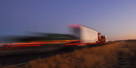 morning scene with truck moving fast with blur and lightsの写真素材