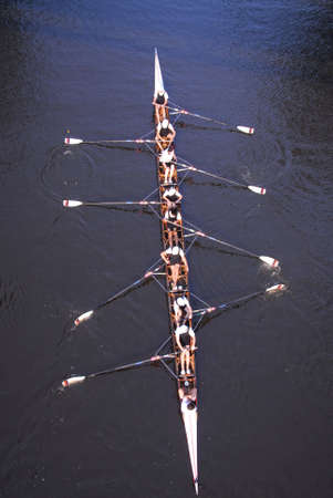 A rowing team pratice rowing in the evening on a smooth and calm river