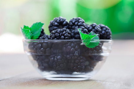 Berries blackberries lying on wooden deck in glass bowl