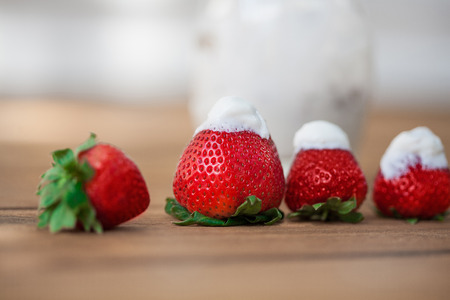 Strawberries and yoghurt in glass lying on wooden deckの写真素材