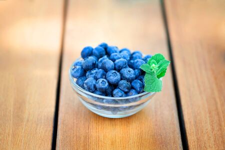 Berries blueberries lying on wooden deck in glass bowlの写真素材