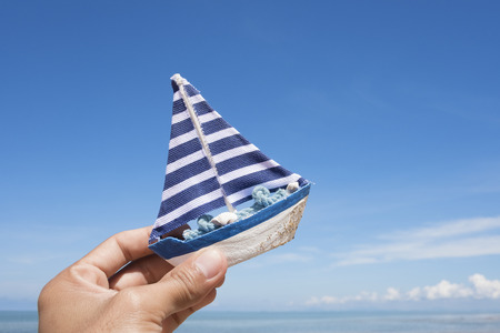 Model boat on sand sea with blue sky backgroundの写真素材