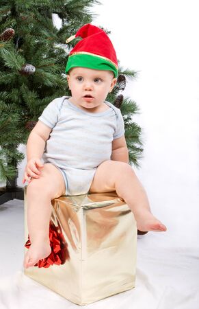 Baby boy sitting on Christmas gift. Studio shoot on white .の写真素材