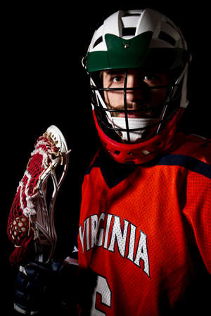 Lacrosse player wearing helmet and holding stick. Studio shoot on the black .の写真素材