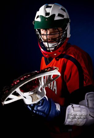 Lacrosse player wearing helmet and holding stick. Studio shoot on the black with blue light spot.の写真素材