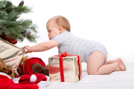 Baby boy reaching for Christmas gifts. Studio shoot on white .の写真素材