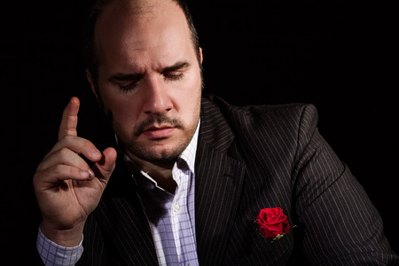 Portrait of man, godfather-like character. Studio shot, black background.の写真素材