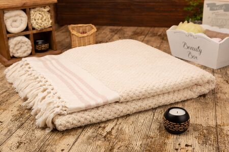 Large handwoven cotton bath towel on wooden background surrounded by bathroom propsの写真素材