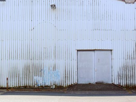 Front of an abandoned, weathered and neglected warehouseの写真素材