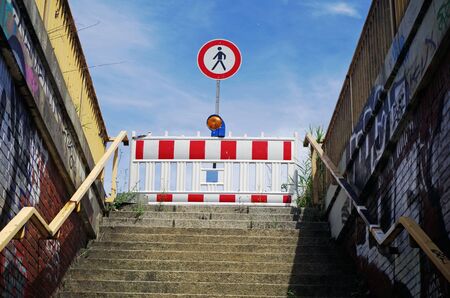 Warning sign at the end of a stairway leading upward, against blue skyの写真素材