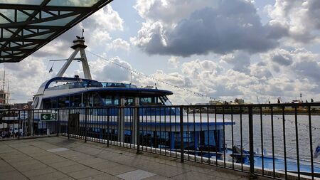 Excursion boat with people on deck at the quayside against cloudy skyの写真素材