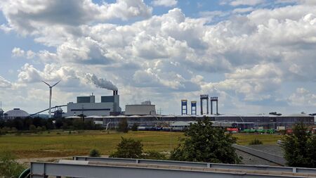 Photograph of an industrial landscape with industrial buildings, railroad tracks and sky against blue cloudy skyの写真素材