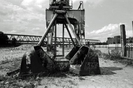 Black and White analog photography of an abandoned industrial landscape with crane and bridgesの写真素材