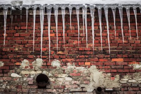 Icicles above the old brick wall at winter