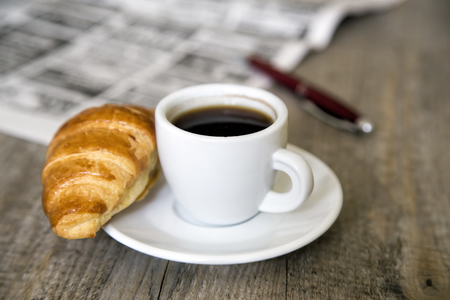 Coffee with croissant and newspaper with penの写真素材