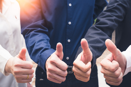 the abstract image of the many businessmen thake a thumbs up during sunrise. the concept of symbol, body language, good, work group, unity and business.の写真素材
