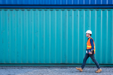 The abstract image of the engineer walking in shipping container yard and copy space. the concept of engineering, shipping, shipyard, business and transportations.の写真素材