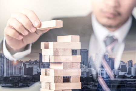 the double exposure image of the businessman lay down one of the building bricks on the tower overlay with cityscape image. the concept of business, structure, stability, success and development.の写真素材