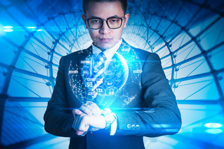 The abstract image of the businessman looking to the virtual hologram on smart watch . the concept of communication network, internet of things and future.の写真素材