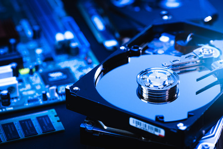 The abstract image of inside of hard disk drive on the technician's desk and a computer motherboard...