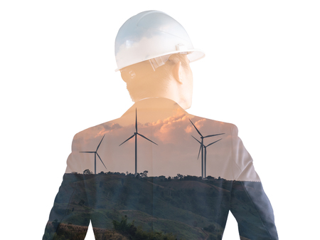 The double exposure image of the engineer standing back during sunrise overlay with wind turbine image. The concept of engineering, power, electricity, environment and future.の写真素材