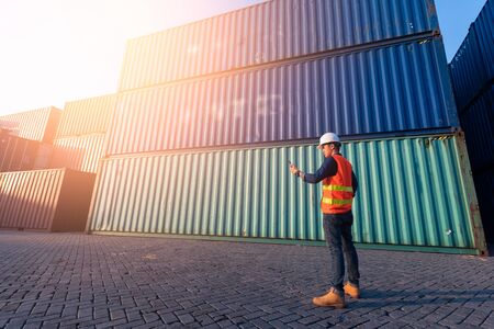 The abstract image of the engineer using a smartphone in shipping container yard and copy space. the...
