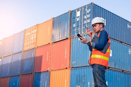 The abstract image of the engineer using a smartphone in shipping container yard and copy space. the concept of engineering, shipping, shipyard, business and transportations.の写真素材