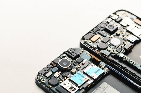 The inside of the smartphone's motherboard and tools lay on the white table. the concept of computer...
