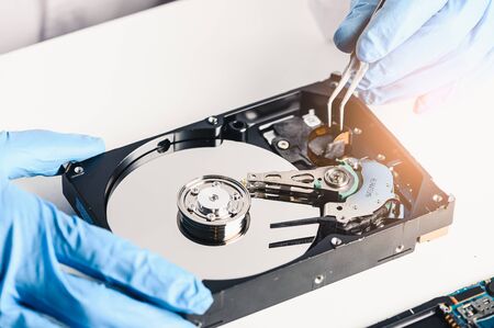 The abstract image of the technician repairing inside of hard disk drive by screwdriver in the lab. the concept of data, hardware, technician and technologyの写真素材
