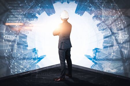 The double exposure image of the engineer standing back during sunrise overlay with cityscape image and futuristic hologram. The concept of engineering, construction, city life and future.の写真素材