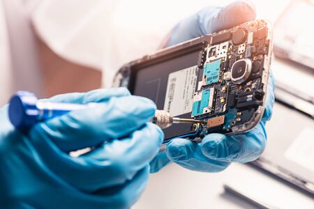 The asian technician repairing the smartphone's motherboard in the lab with copy space. the concept of computer hardware, mobile phone, electronic, repairing, upgrade and technology.の写真素材