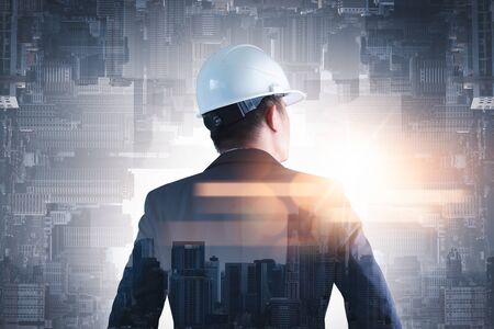 The double exposure image of the engineer standing back during sunrise overlay with cityscape image. The concept of engineering, construction, city life and future.の写真素材