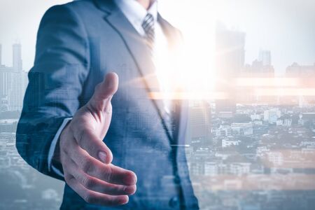 The double exposure image of the businessman handshaking with another one during sunrise overlay with cityscape image. The concept of modern life, business, city life and partnership.の写真素材