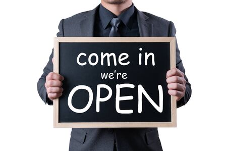 the businessman holding an opening board sign. the concept of new normal, reopening, economic and business.の写真素材