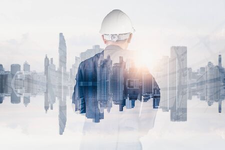 The double exposure image of the engineer standing back during sunrise overlay with cityscape image. The concept of engineering, construction, city life and future.の写真素材