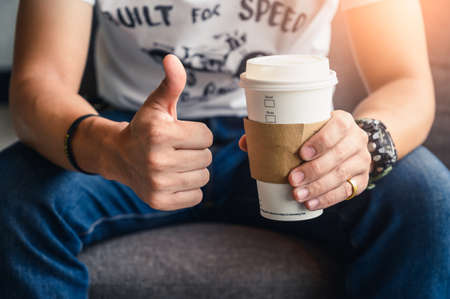 the man holding the recyclable coffee cup and make thumb up