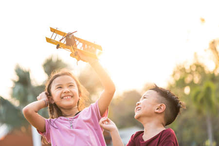the kids playing the airplane toy in the park during sunrise.