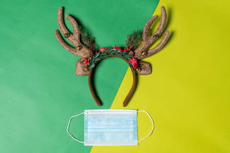 the Christmas props and the protective mask laying on the color backdrop. the concept of festival, pandemic, celebrating, coronavirus and Christmasの写真素材