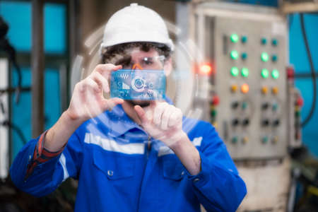 the worker working with automation robot in the factory by the futuristic hologram. the concept of...