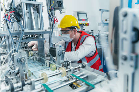 the manufacturing of the medical face mask in the factory via the machine. the concept of COVID-19,...