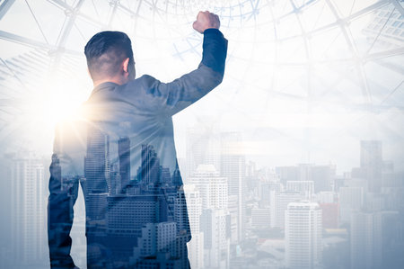 The double-exposure image of the businessman standing back during sunrise overlays with the cityscape image. The concept of modern life, business, city life, and the internet of thの写真素材