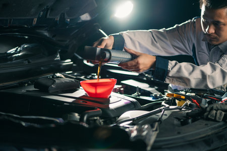 the technician maintained and refilled the lubricant for the car's engine in the garage. the concept of engineering, transportation, petroleum and automobilesの写真素材
