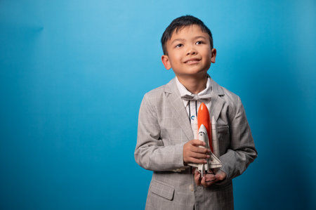 the studio shot isolated image of the boy playing the miniture space rocket with the blue backdrop