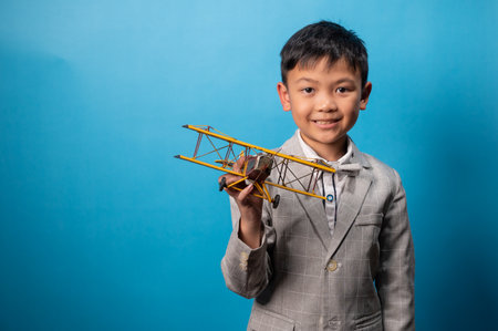the studio shot isolated image of the boy playing the miniture airplane with the blue backdrop