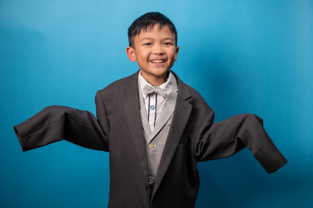 Portrait of happy asian boy in suit on blue background.の写真素材