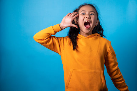 the studio isolated a portrait image of the acting of a happy girl with a blue backdrop.の写真素材