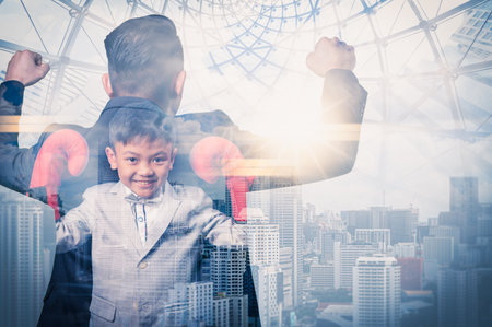 the double exposure image of the boy wearing the boxing gloves and overlay with cityscape and businessman imageの写真素材